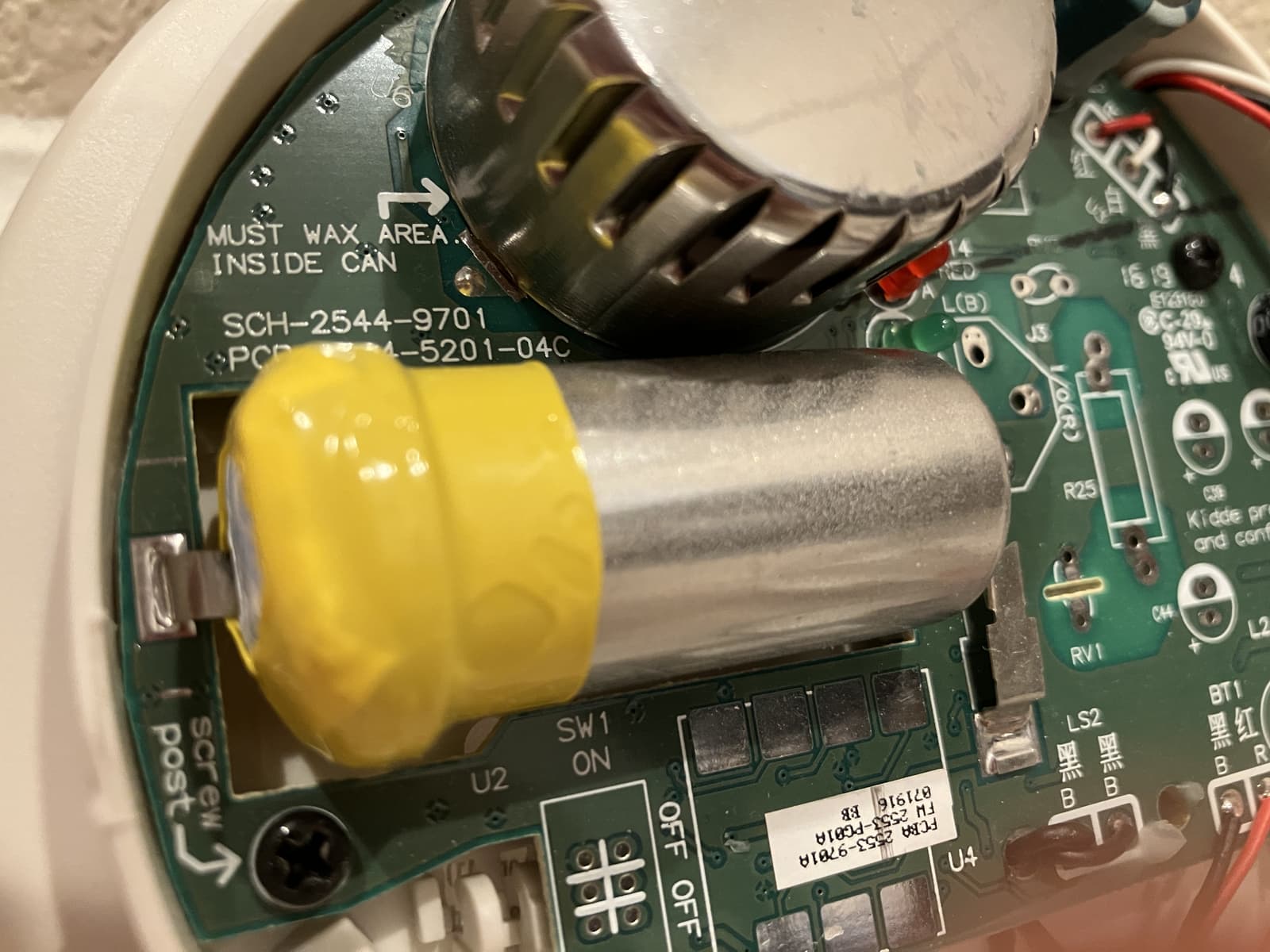 The opened inside of a smoke and carbon monoxide alarm, showing its sensor and circuit board.