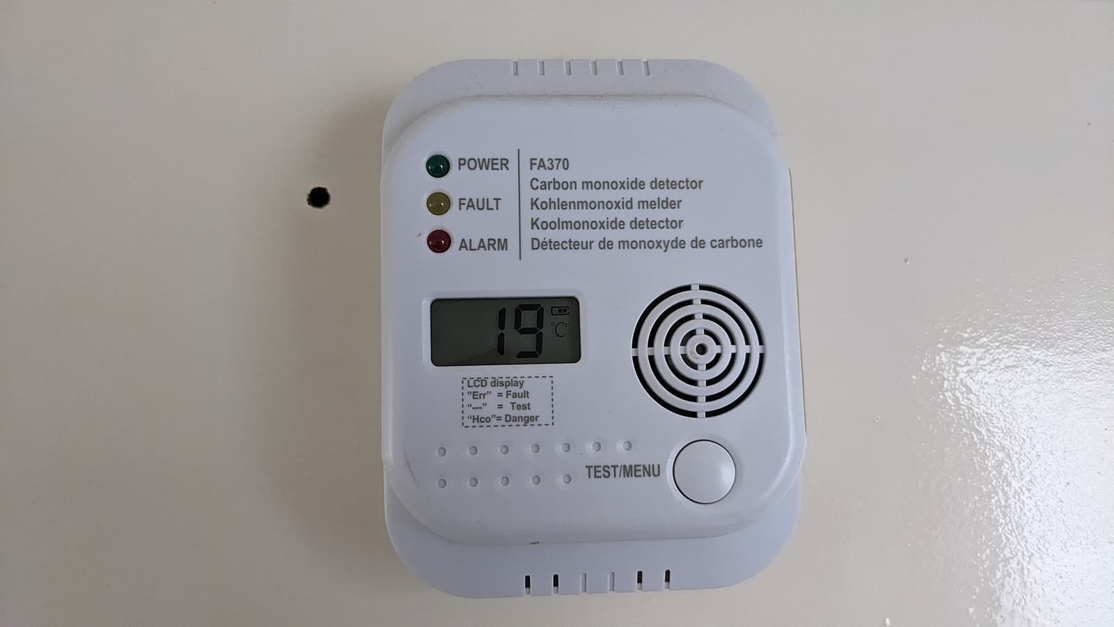 A carbon monoxide alarm with a digital display mounted on a wall.