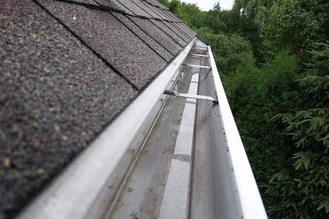 A clean, empty gutter running along the edge of a shingled roof.