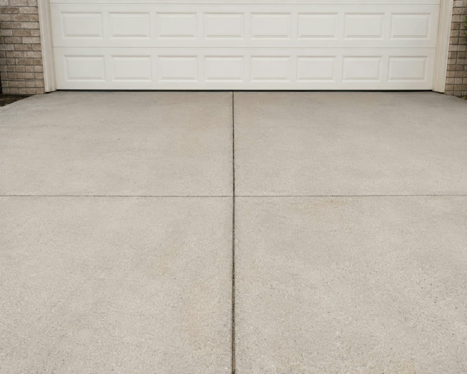 A clean concrete driveway in front of a white garage door.