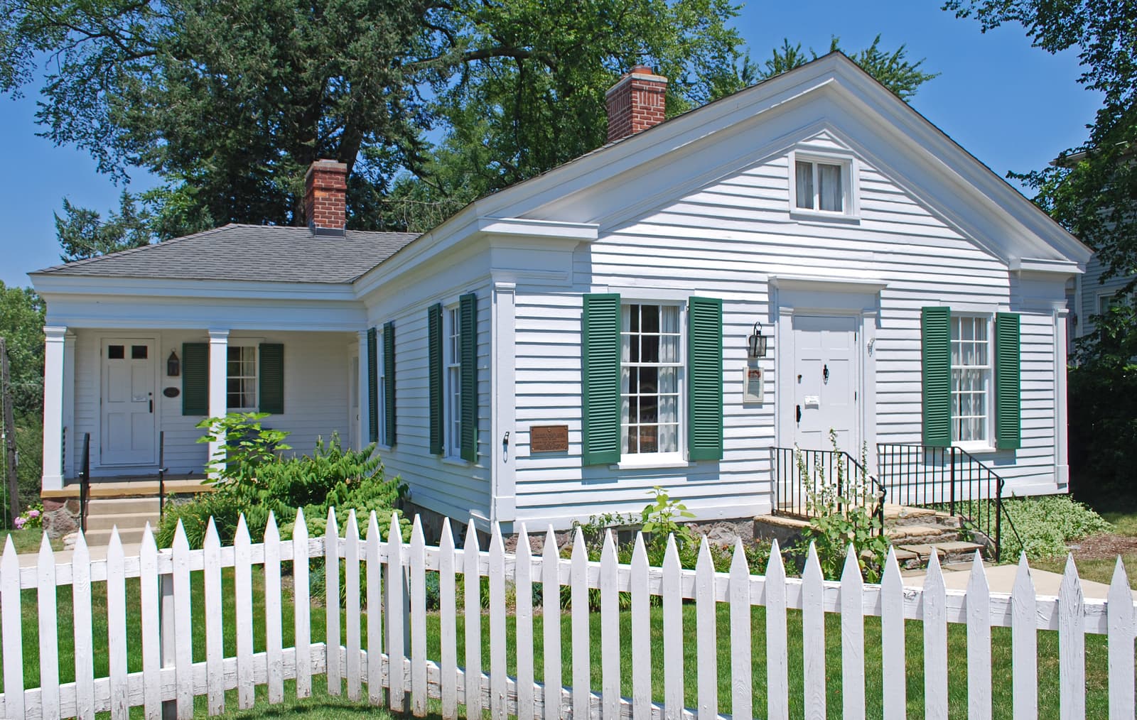 The John W. Hunter House in Birmingham, Michigan, a white clapboard house with green shutters behind a picket fence.
