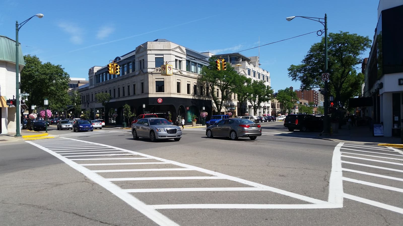 A crosswalk and cream-colored storefront buildings at an intersection in downtown Birmingham, Michigan.