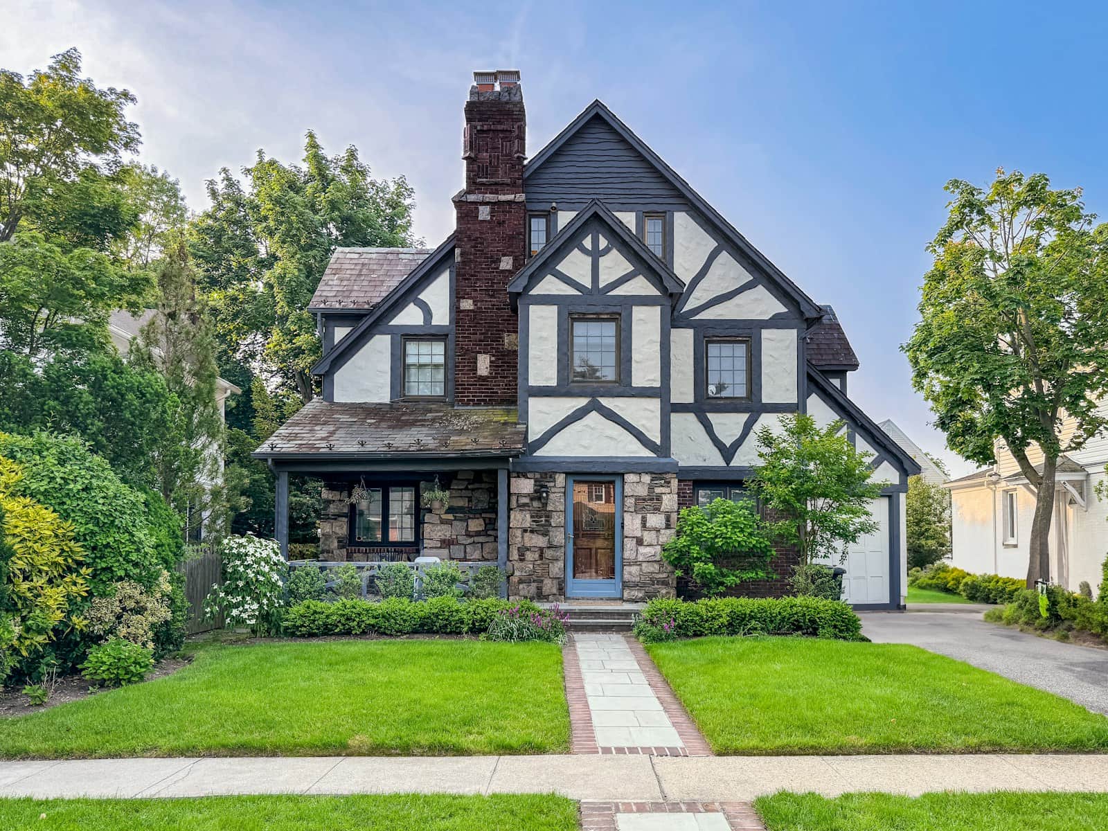 A Tudor-style house with half-timbered gables, a stone lower story and a tall brick chimney.