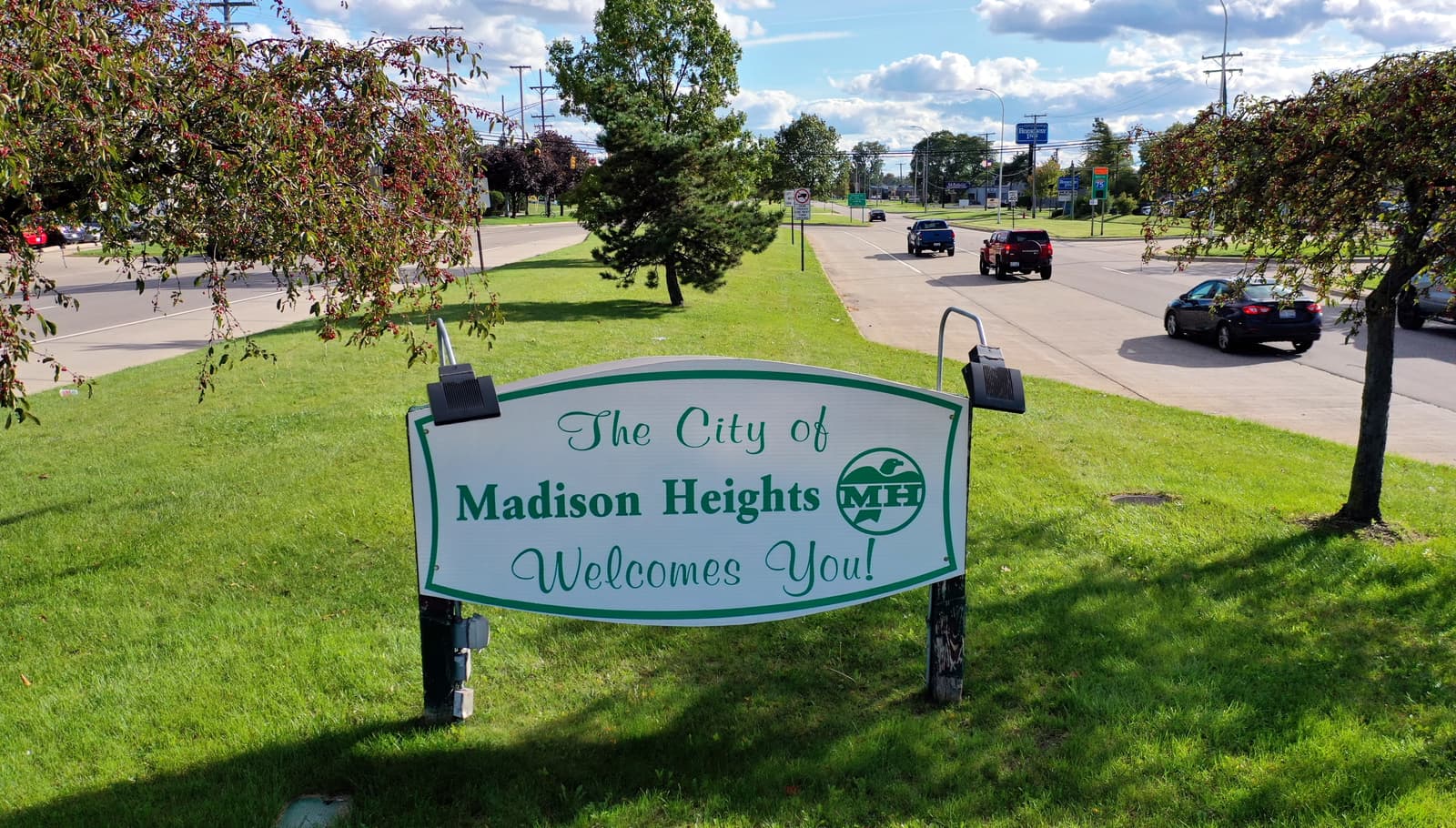 The City of Madison Heights welcome sign on a grass median beside a divided road.