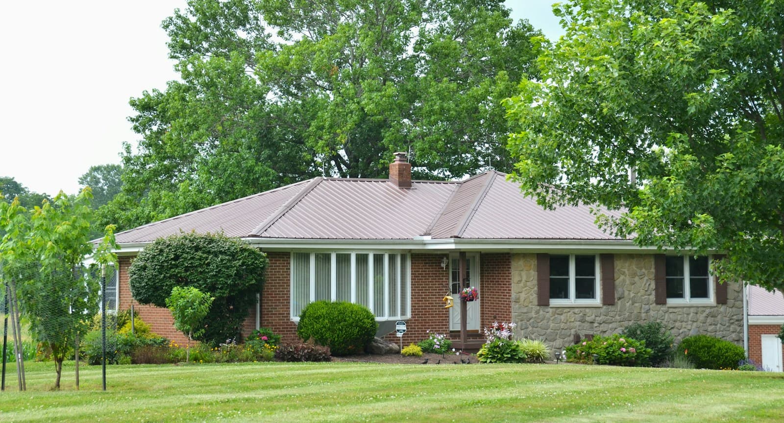 A low brick ranch house with a wide picture window and a stone section by the door.