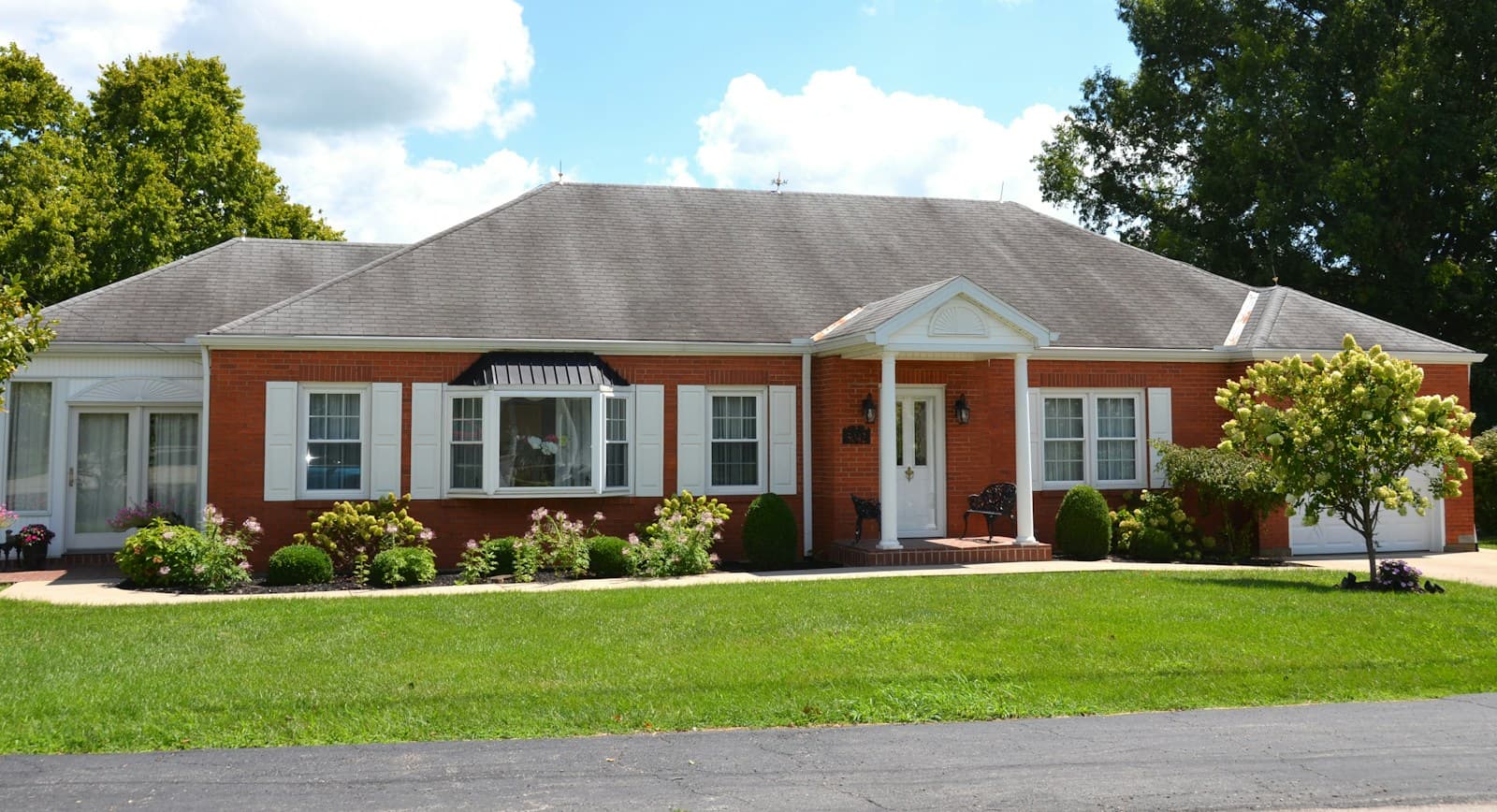 A long brick ranch house with a columned entry on a wide lawn.